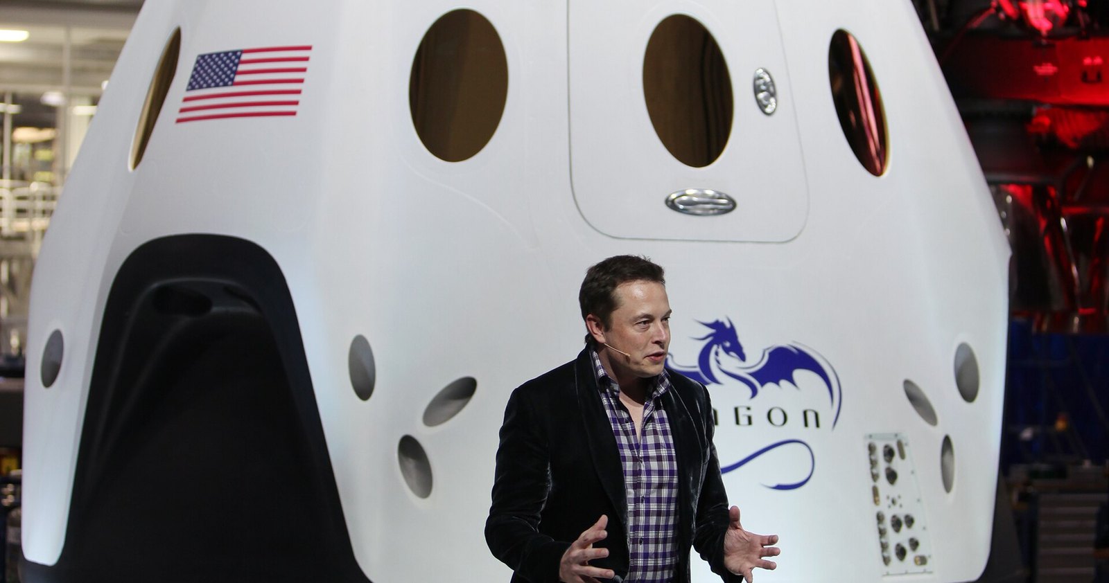 Elon Musk speaks in front of SpaceX's white Dragon V2 crew capsule, which bears an American flag and the Dragon logo, at the company's Hawthorne, California, headquarters in 2014.